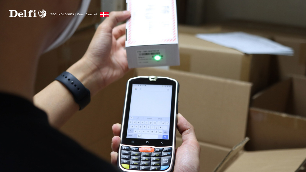 Nhân viên kho cầm máy PDA kiểm hàng giữa các kệ trong kho bán lẻ