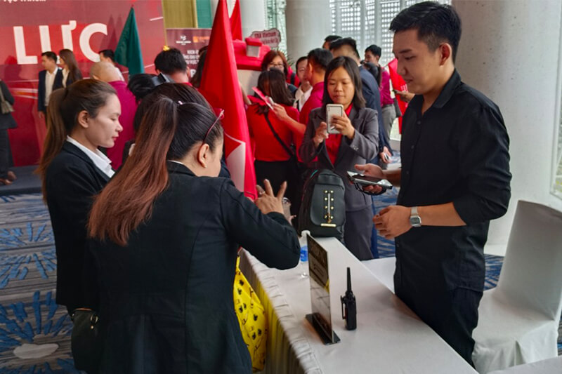 Nhân viên đang hỗ trợ và hướng dẫn khách tham dự đăng ký tại quầy tiếp tân sự kiện.