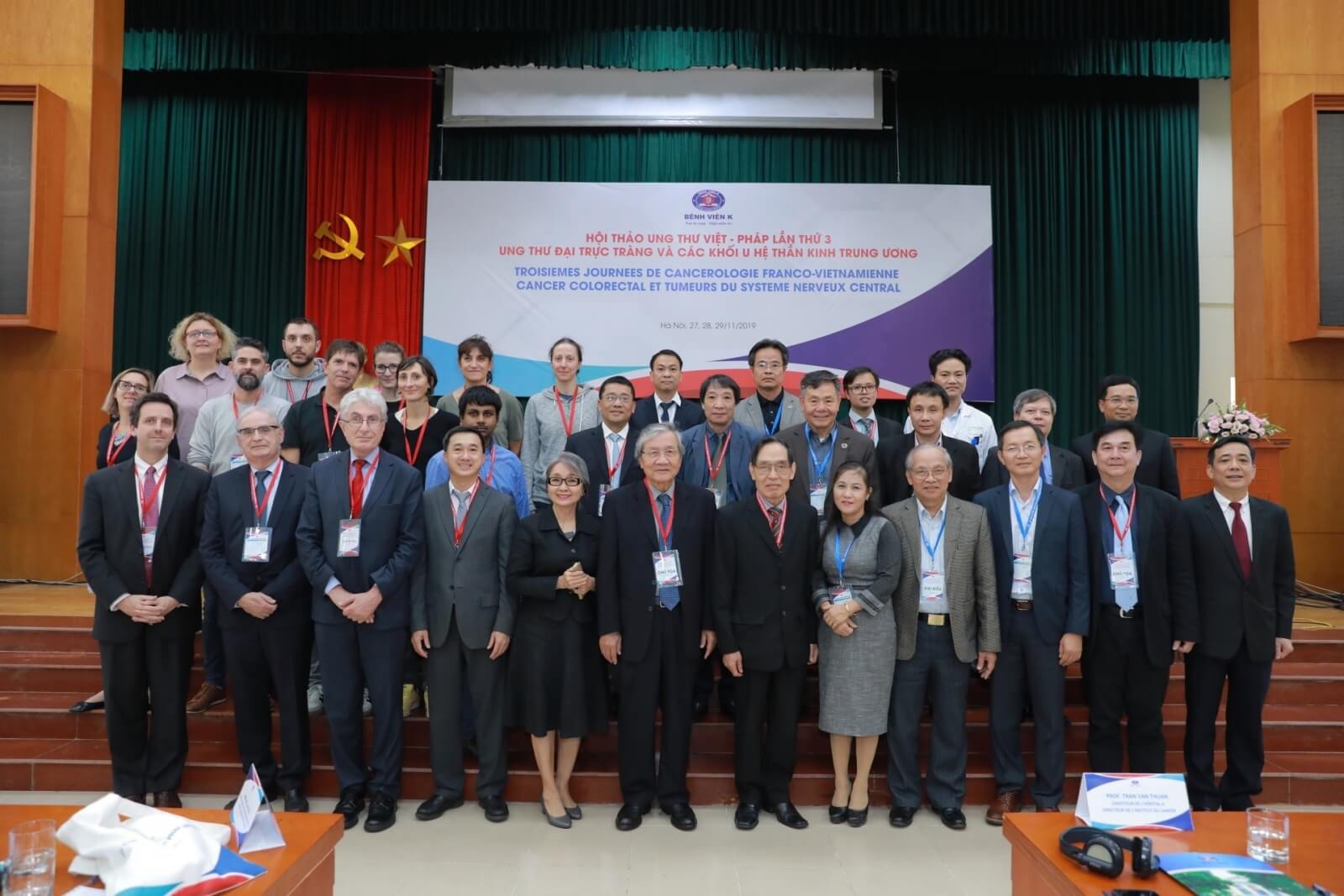 Khách mời đang chụp ảnh tập thể tại hội thảo ung thư Việt - Pháp cùng sân khấu chương trình phía sau