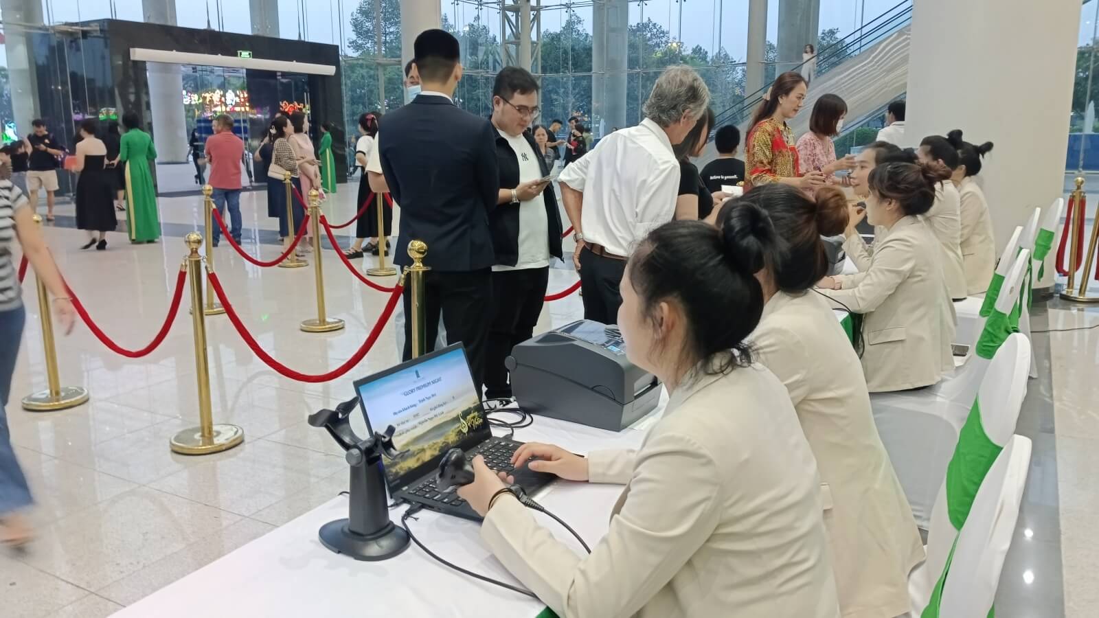 Nhân viên đang hỗ trợ khách check-in tại khu vực tiếp đón khách của sự kiện
