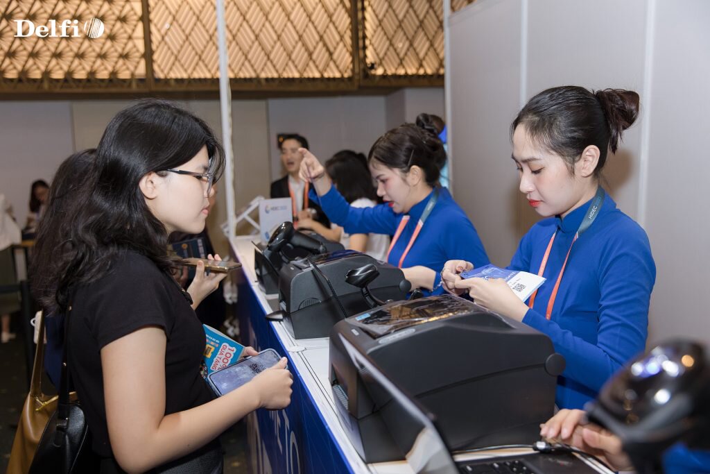 Nhân viên đang hỗ trợ khách check-in tại quầy tiếp đón hội nghị HIDEC 2023