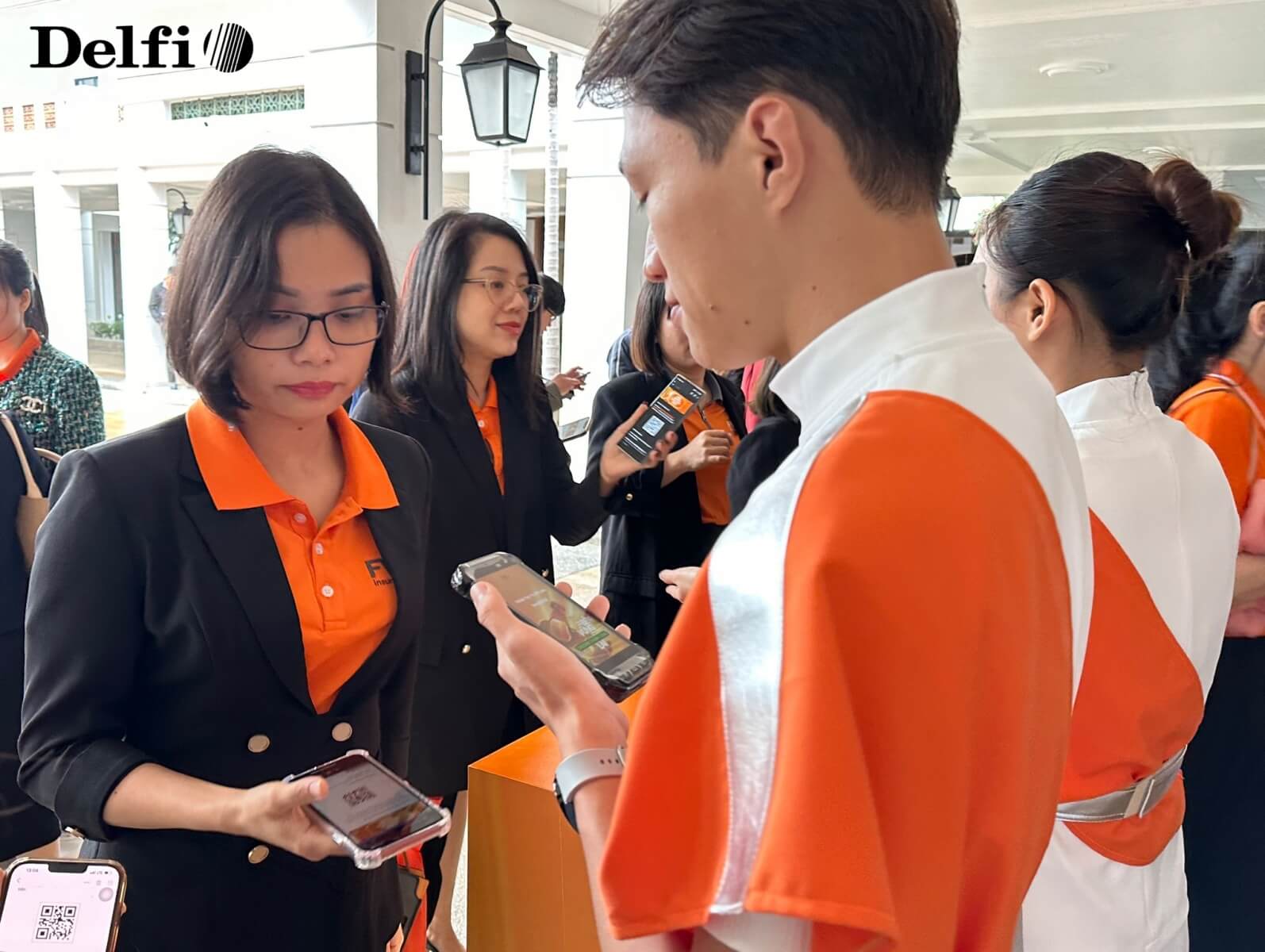 Nhân viên sự kiện đang hỗ trợ khách tham dự kiểm tra mã check-in bằng điện thoại tại khu vực tiếp đón