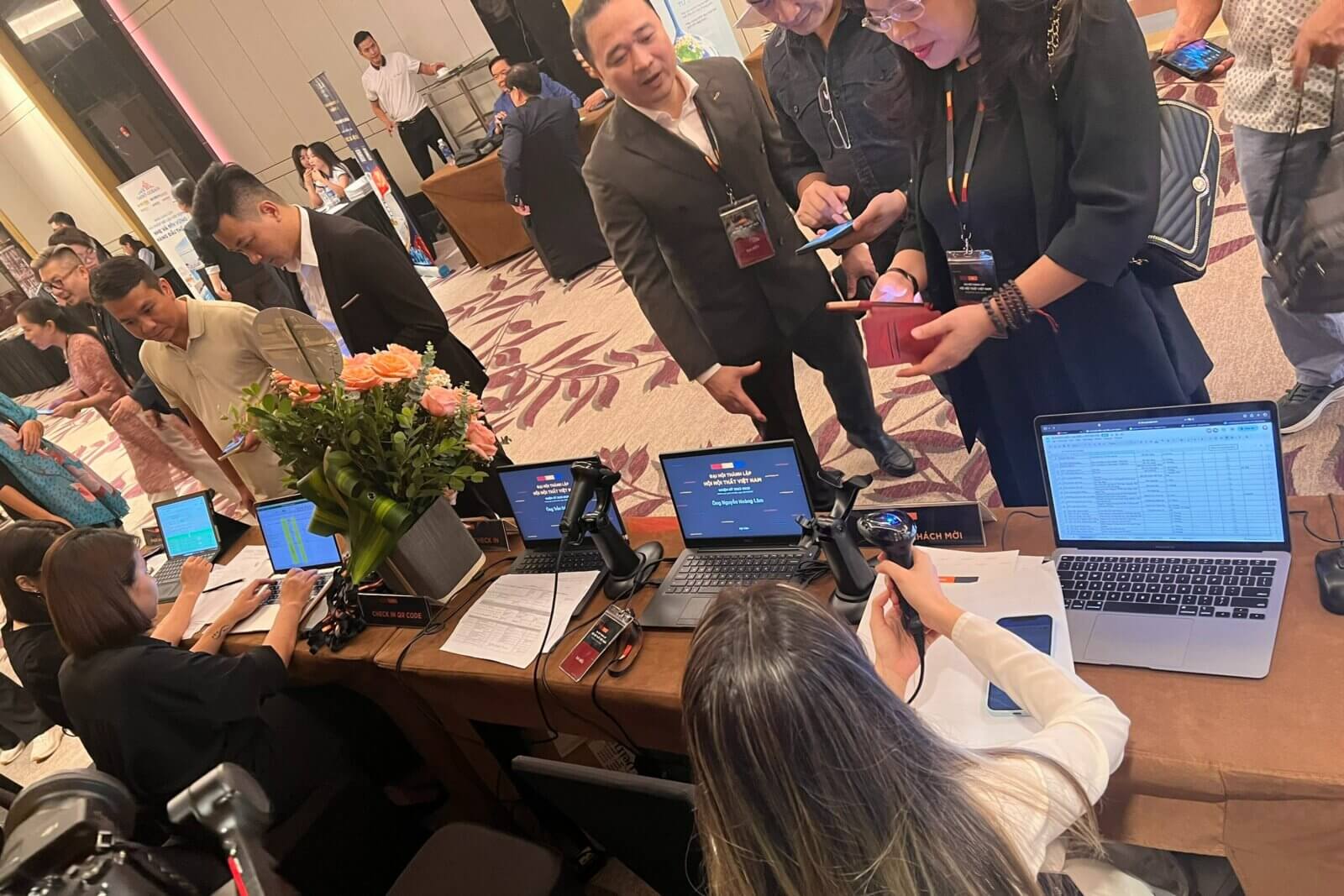 Khách tham dự đang thực hiện check-in QR code tại bàn đăng ký sự kiện